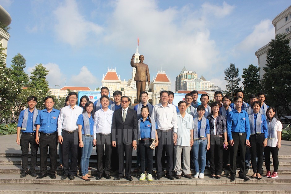 Volunteers take a photograph with Ho Chi Minh city leaders at the President Ho Chi Minh statue. (Photo: hcmcpv.org.vn)
